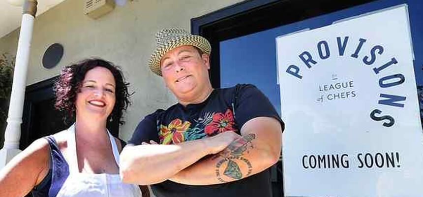 Two people posing in front of League of Chefs sign